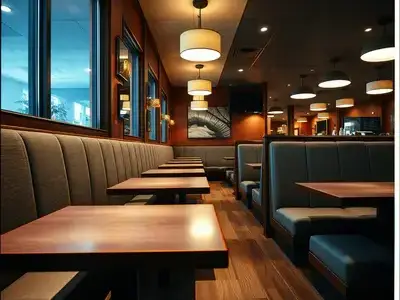 Wide angle view of a restaurant booth seating area with newly upholstered bench seats in durable gray fabric, warm restaurant lighting